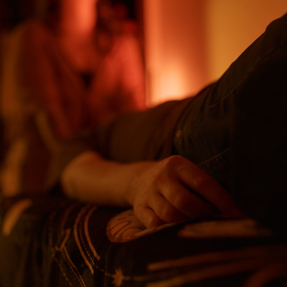 A client's hand resting on the sound bed, Alicia working behind