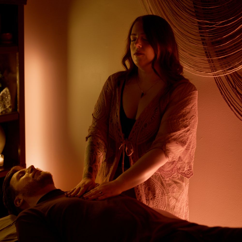 Alicia with her hands on a client's shoulders during a sound bed session